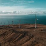 drone shot of windmills near body of water