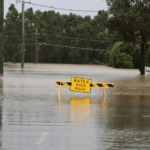 photo of flooded australian road with sign "water over road"