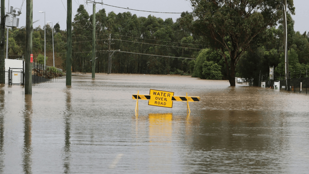 photo of flooded australian road with sign "water over road"